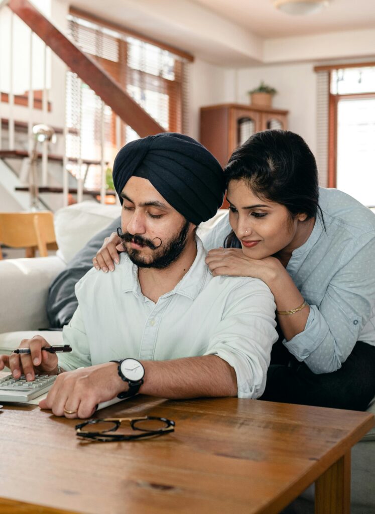 A loving couple managing their finances together, using a calculator at home.